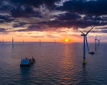 Schepen in windpark bij zonsondergang